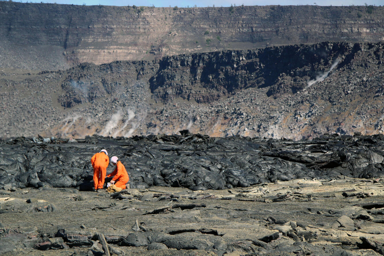 Color photograph of scientists collecting sample on crater floor