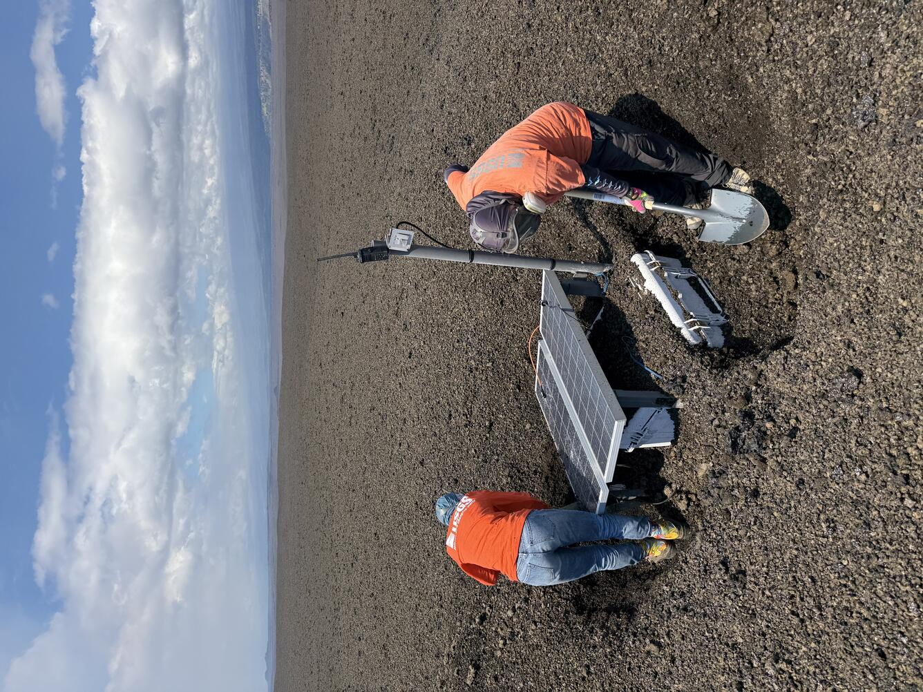 Color photograph of scientists fixing volcano monitoring equipment