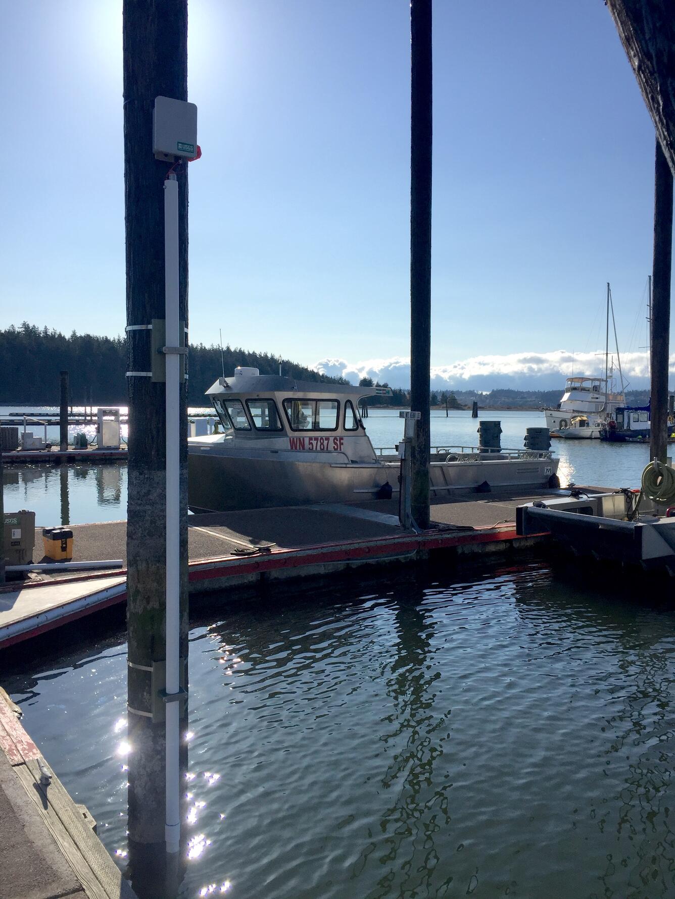 View of a dock in the water with poles near each dock section and boats secured to the dock sides.