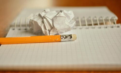 Image of pencil and crumpled paper on gridded paper notebook