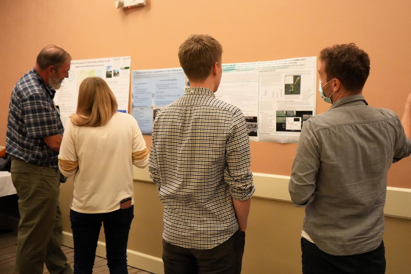 Four scientists discuss posters at a meeting