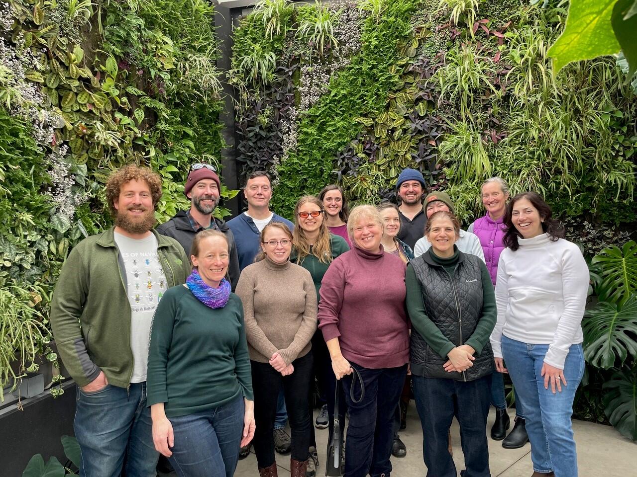 Powell Center working group - group of people smiling in front of a green background