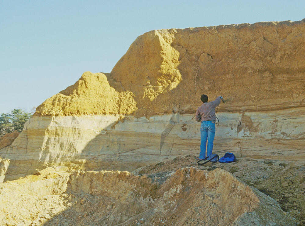 USGS Scientist standing in front of a quarry wall