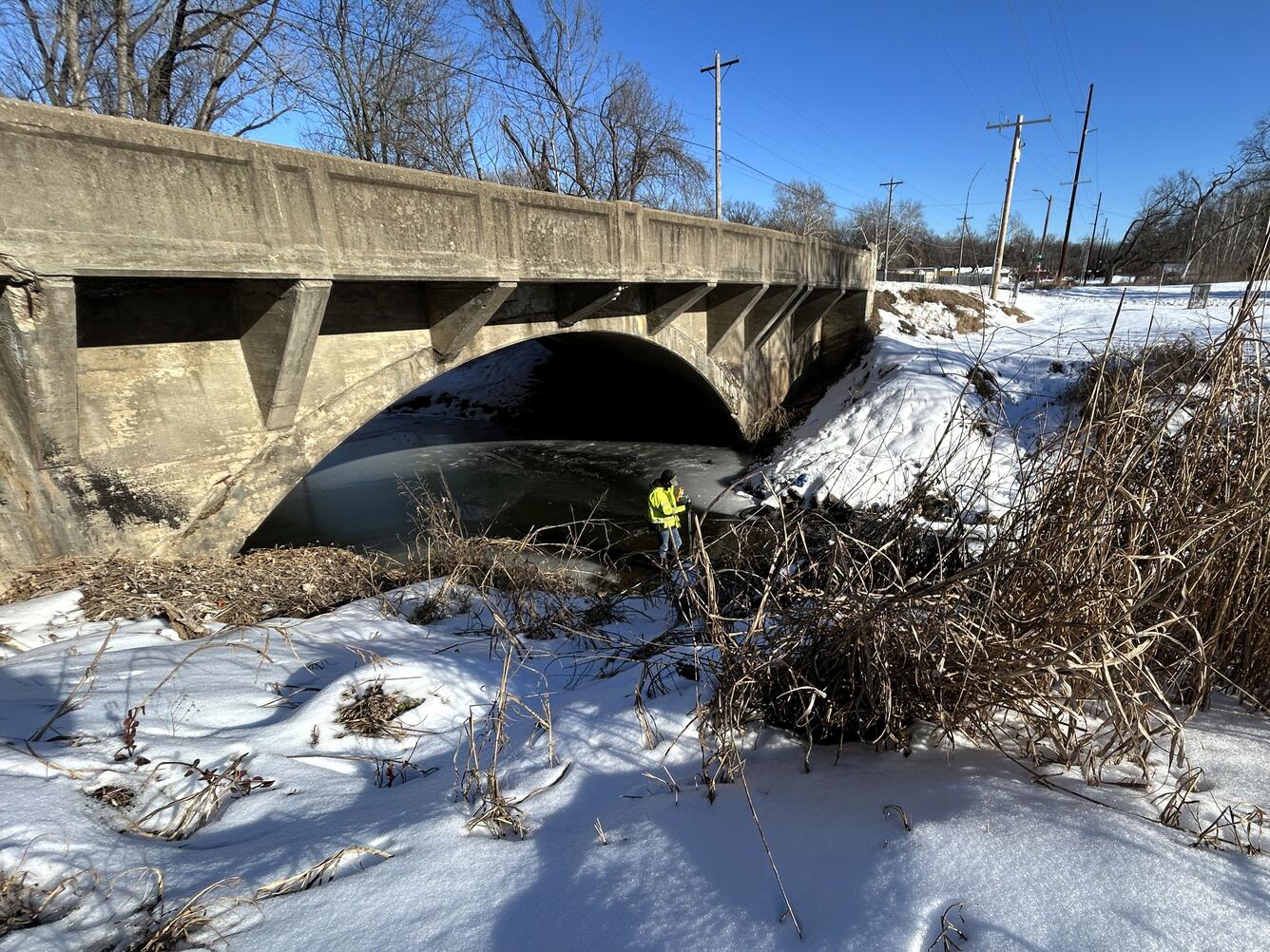 Scientists conducting discharge measurement in middle of stream during winter
