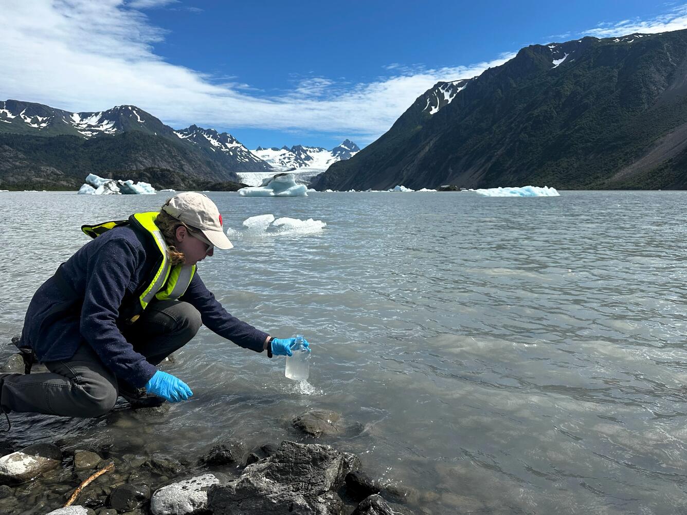 Scientist takes a water sample from a glacial lake in Alaska