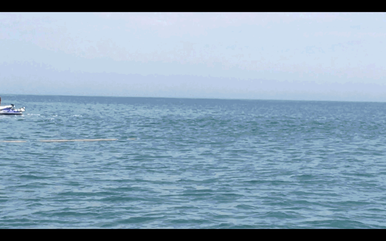 A seismic instrument on pontoon floats is deployed from the beach to the water. 