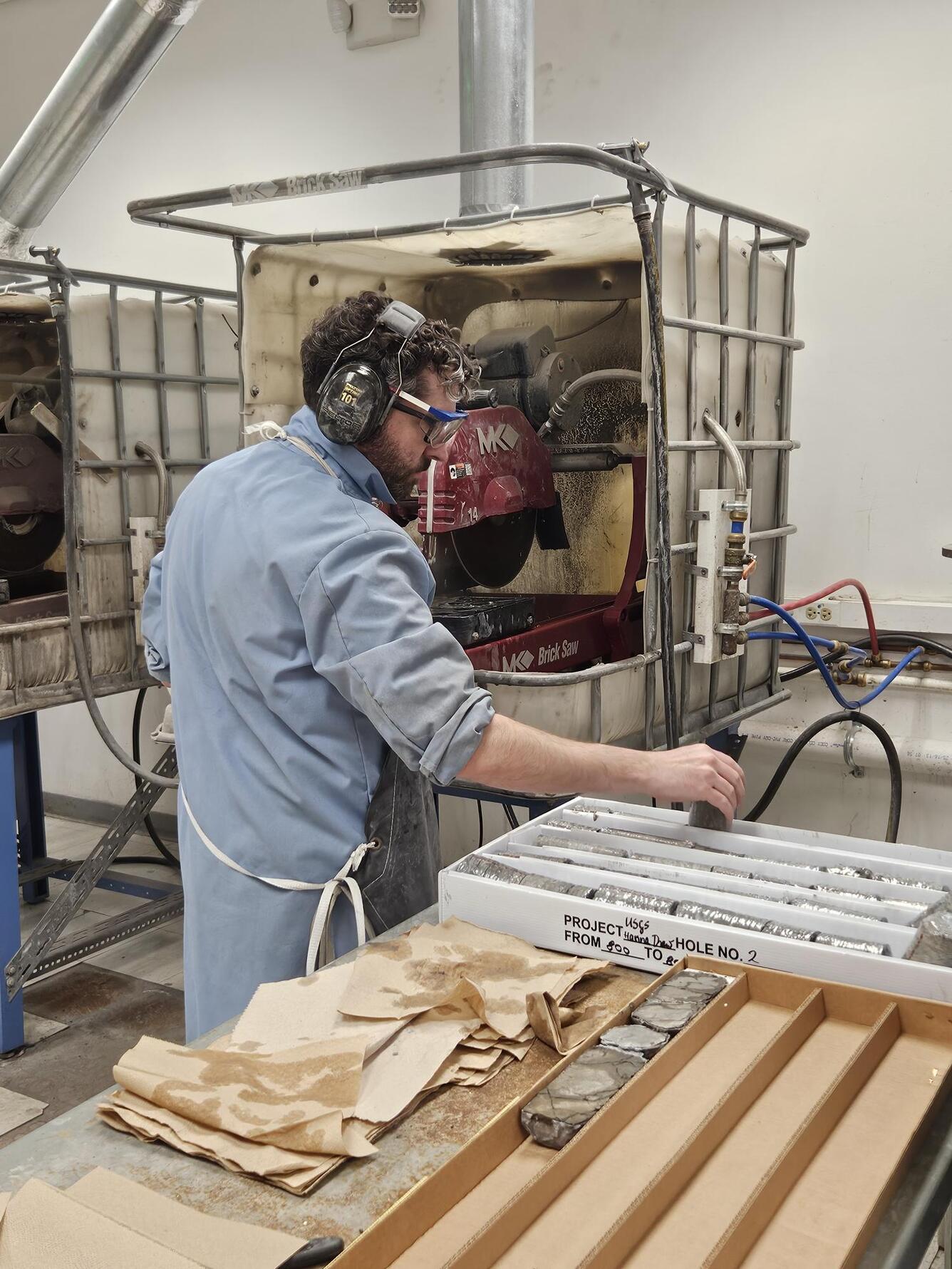 Scientist cuts a rock core with a saw and places into boxes