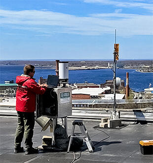 Midsection of image: Sam Banas performing a calibration test of a precipitation tipping bucket instrument