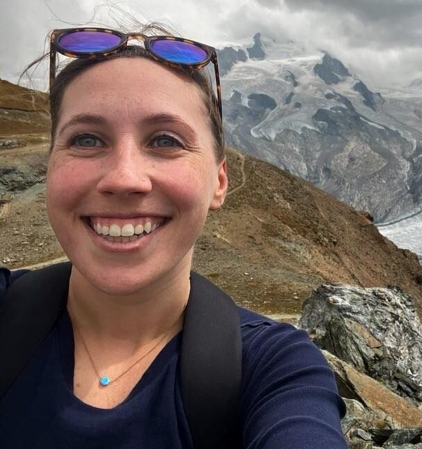 Female biologist with mountains in the background and sunglasses on her head