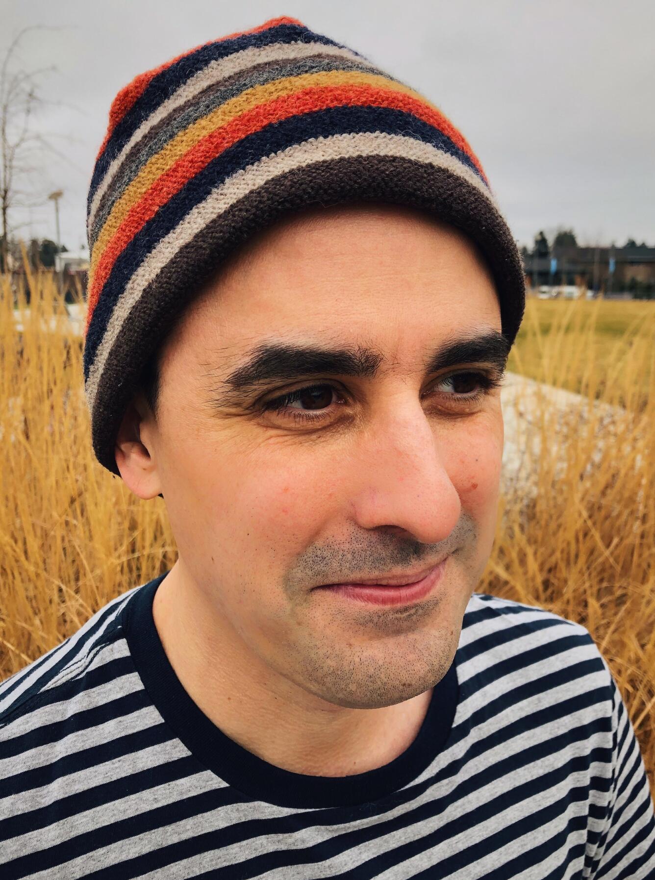 person with striped hat, striped shirt, brown hair and brown eyes