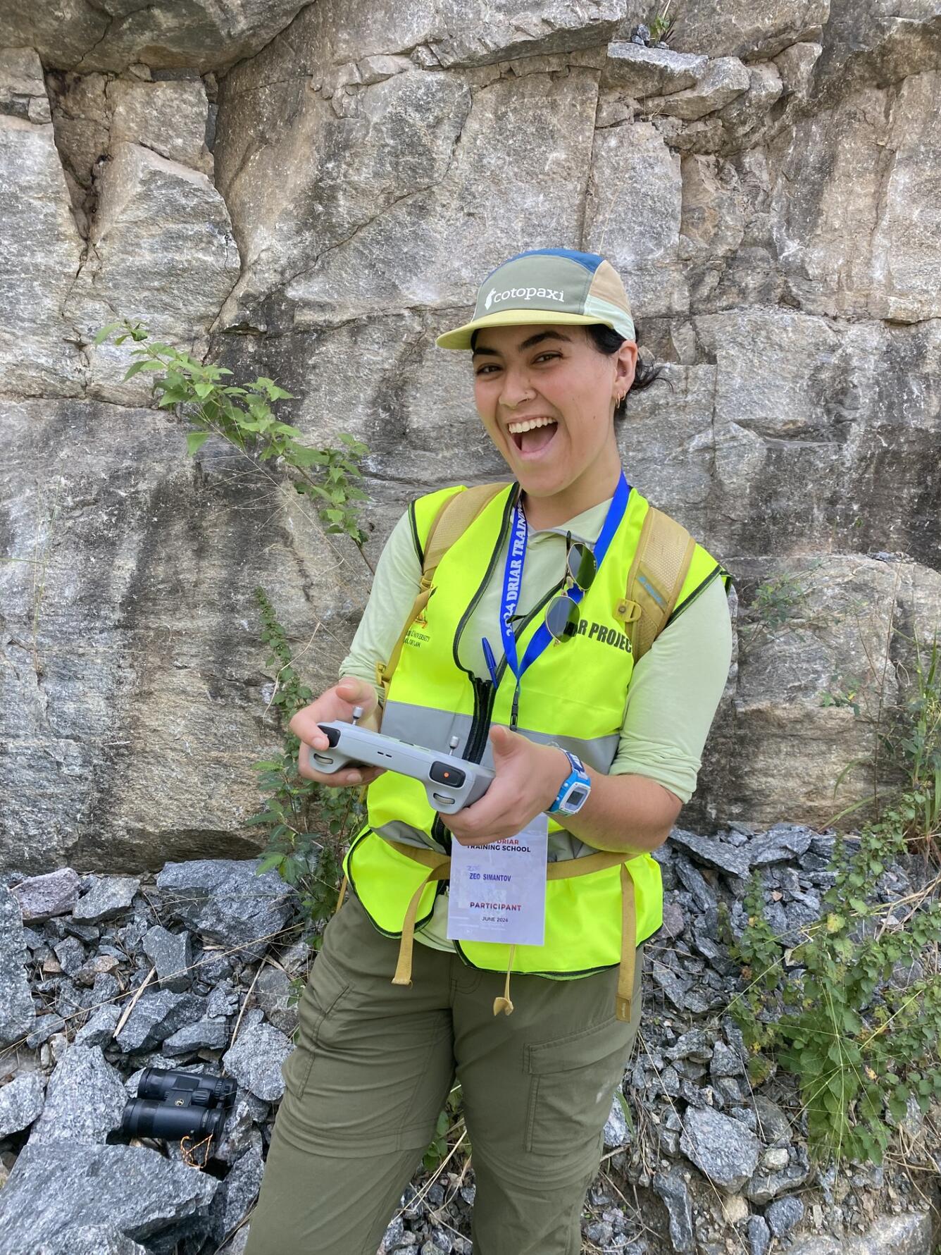 Woman in yellow vest in front of rock