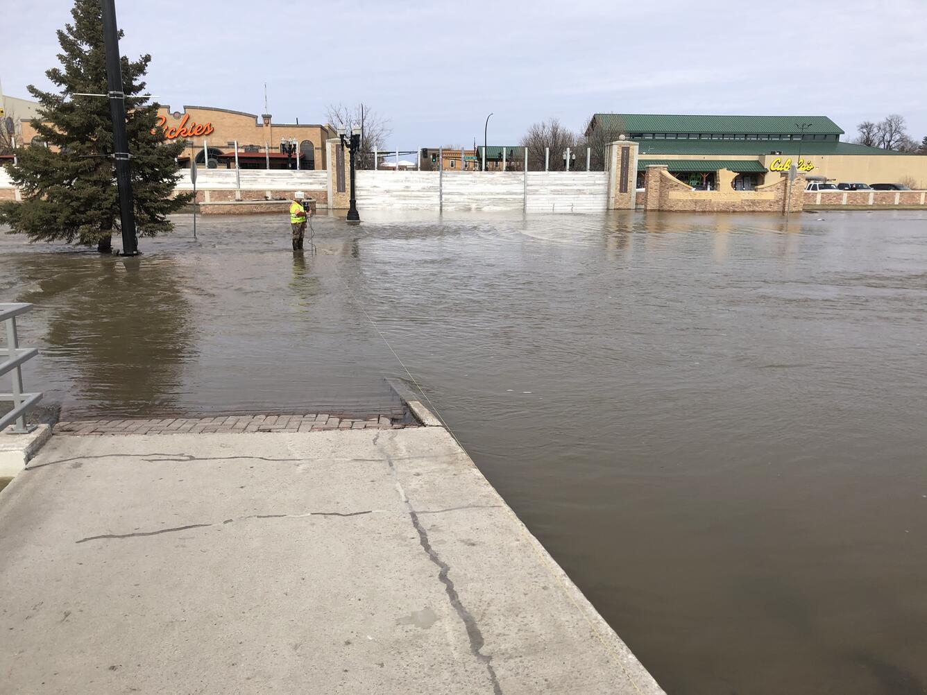 USGS hydrographer Josh Sundberg measures Red River water flowing over the road in East Grand Forks, Minnesota.