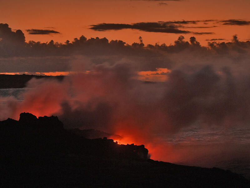 This is a photo of small ocean entries of lava creating a glow that nearly matches the color of the predawn sky.