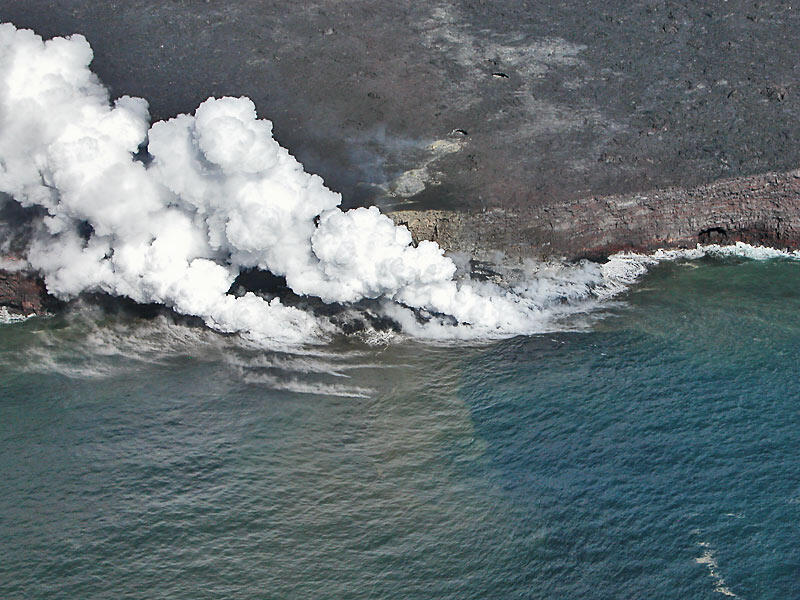 This is a photo of a head-on aerial view of new lava delta and sea cliff behind.