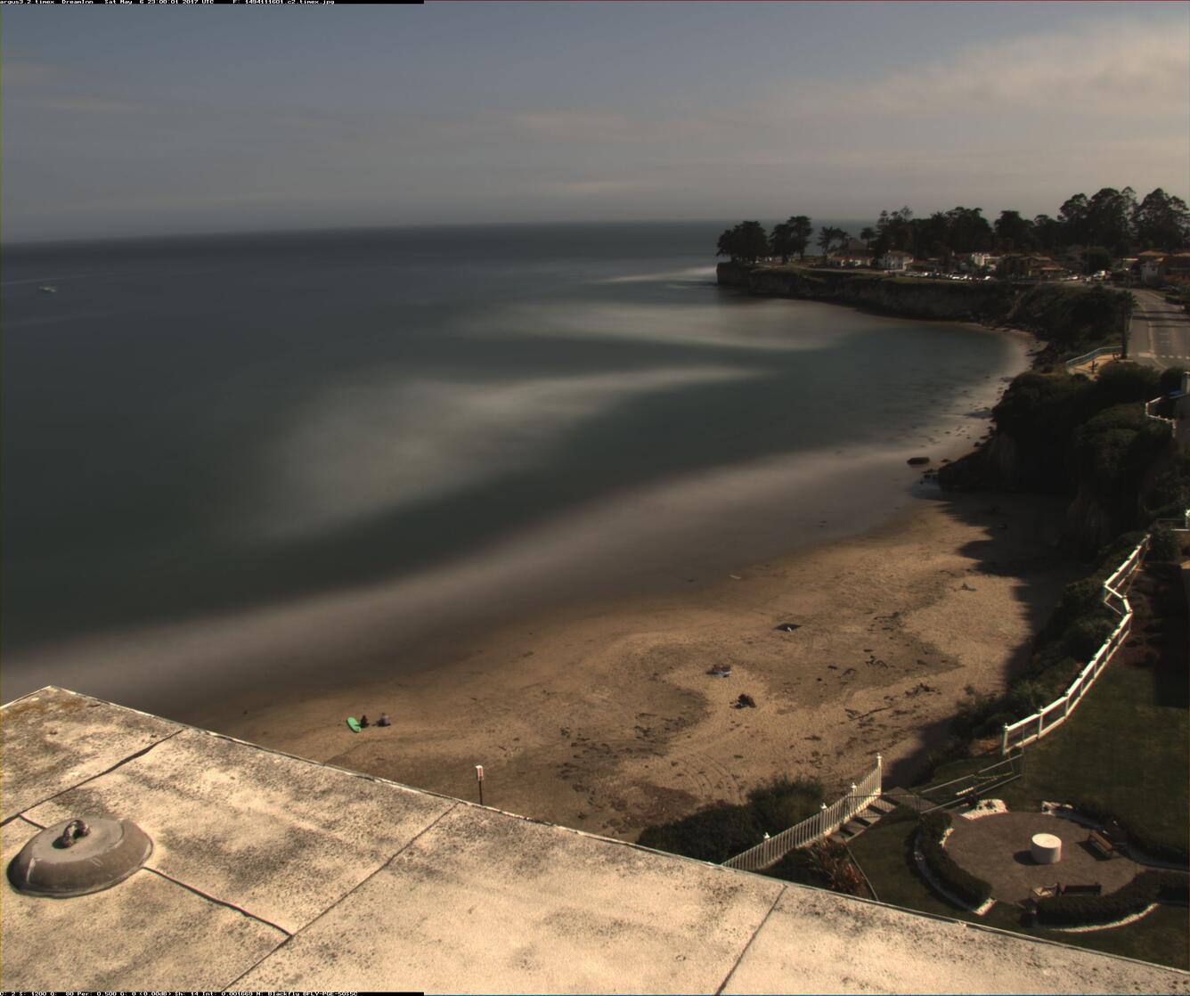 Distant view of the shore from a flat rooftop that is visible at bottom of image.