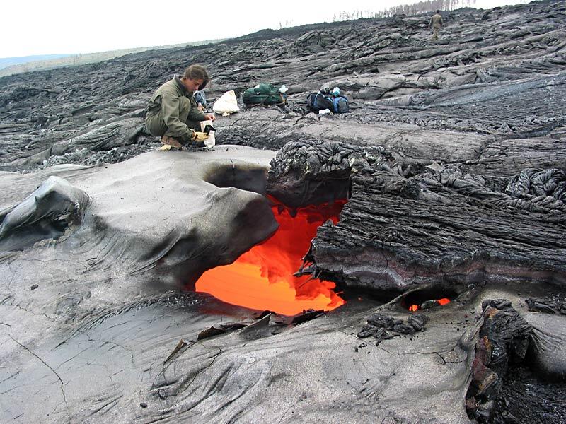 This is a photo of a HVO volunteer putting a sample of quenched lava into a bag.