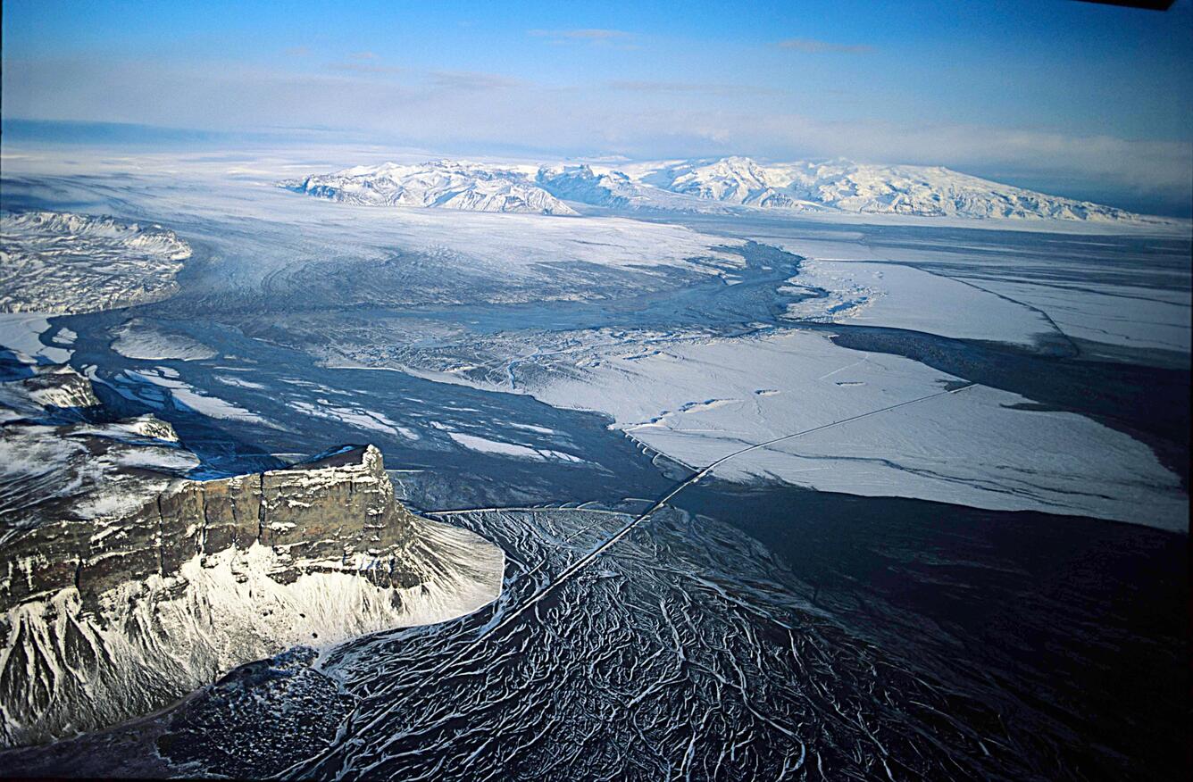 Image shows a flood of water surrounded by mountains and ice. 