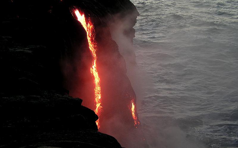 Cascade with lava visible most of way down sea cliff.