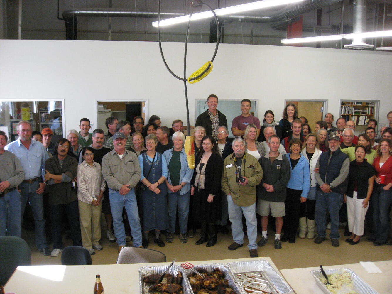 A large group of people gather together in a large warehouse space for a group photo.