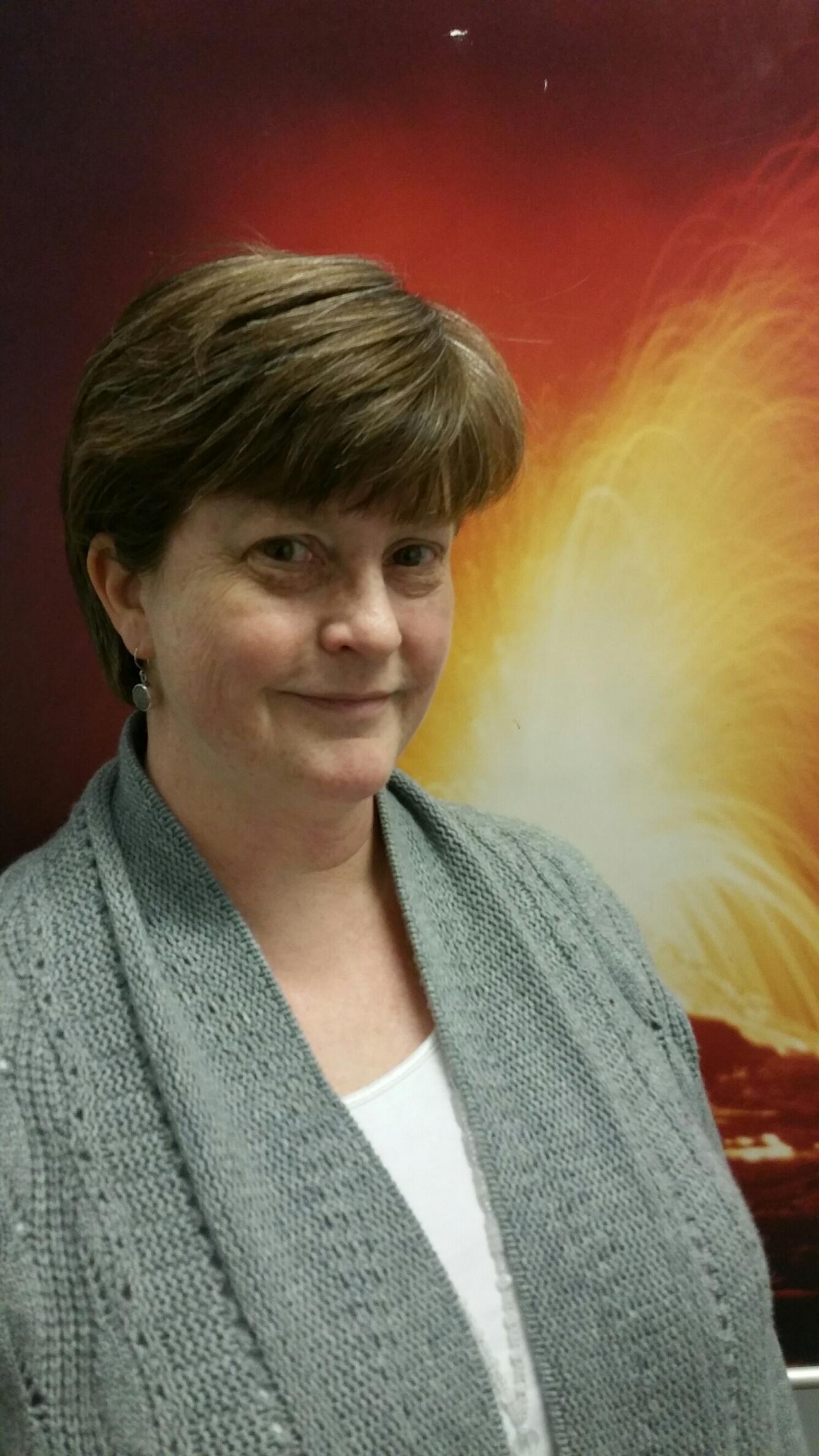Victoria in front of a photo of Kilauea Volcano, HI, in eruption