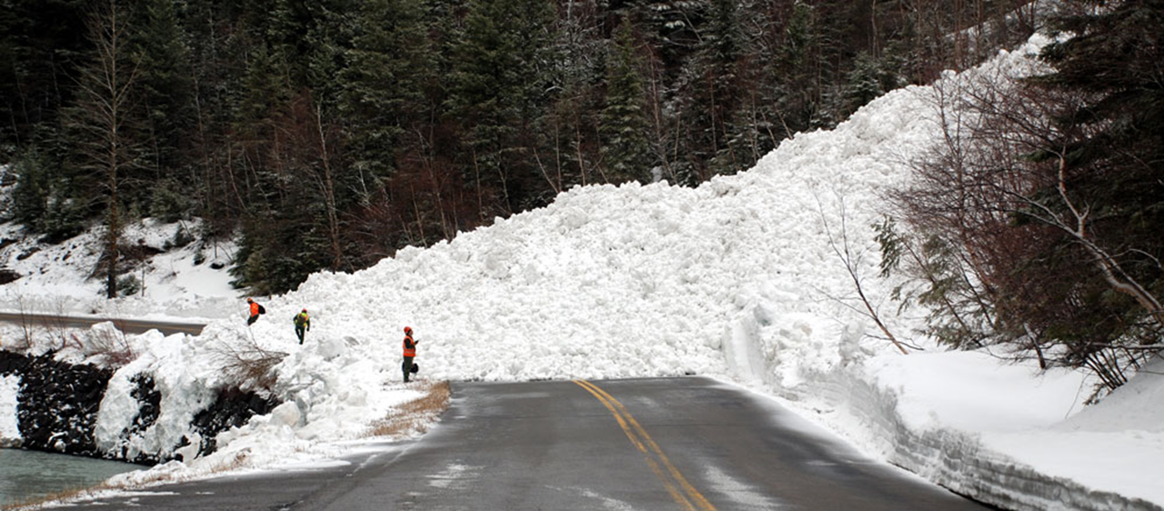 mountain road with huge pile of snow from avalanche piled on top