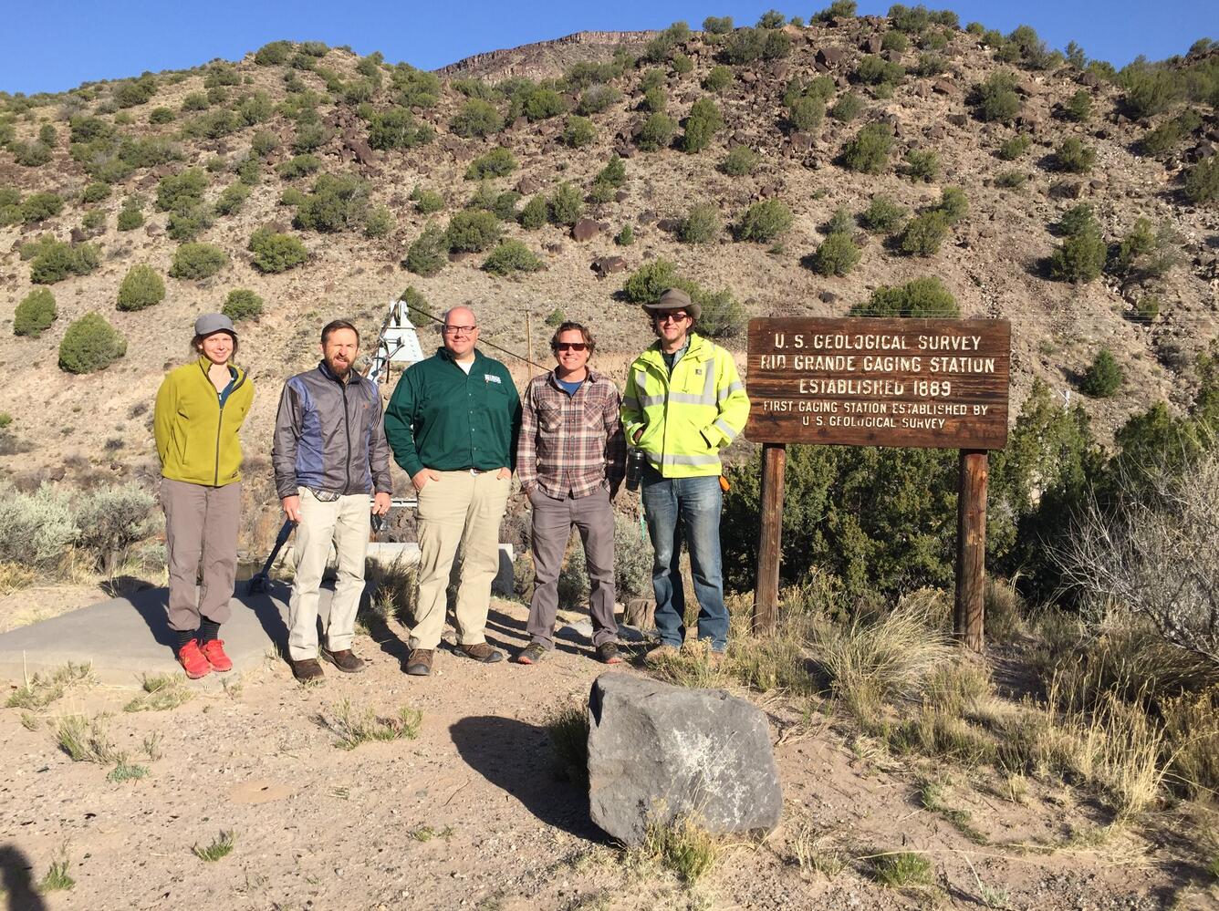 USGS Staff pose next to "First Gaging Station" sign