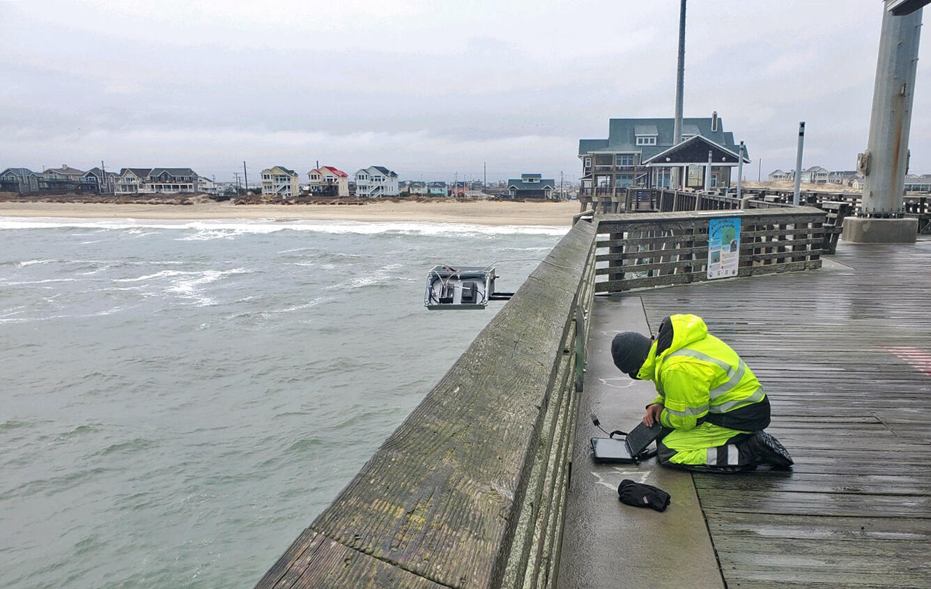 A USGS hydrologic technician tests a new piece of equipment on a pier in North Carolina.