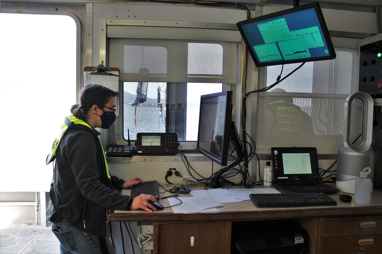 A USGS scientist processing data on a computer during a water sampling cruise.