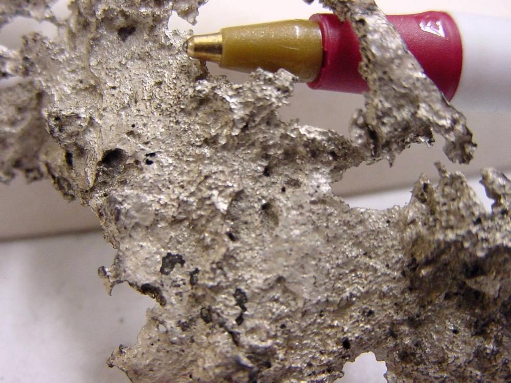 Silver metal specimen with pen for scale