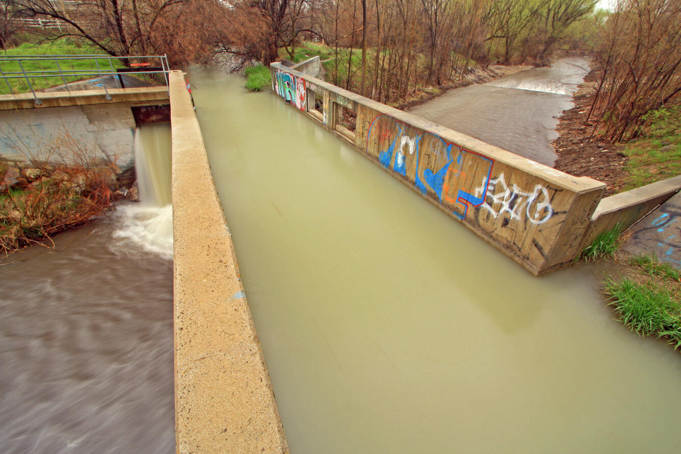 Graffiti on canal wall crossing over a urban creek