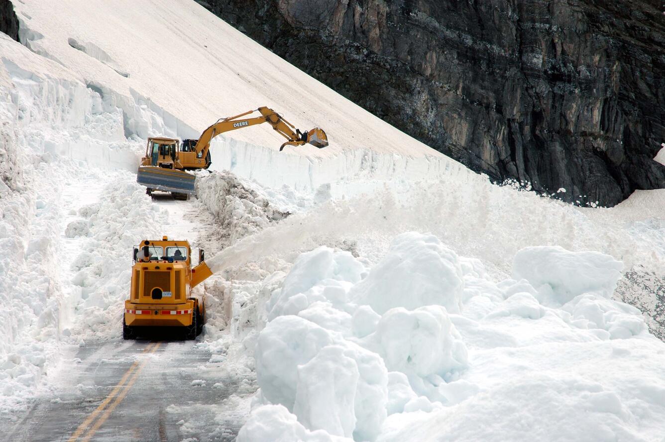 road crews with heavy equipment remove snow that was at least 20 feet deep