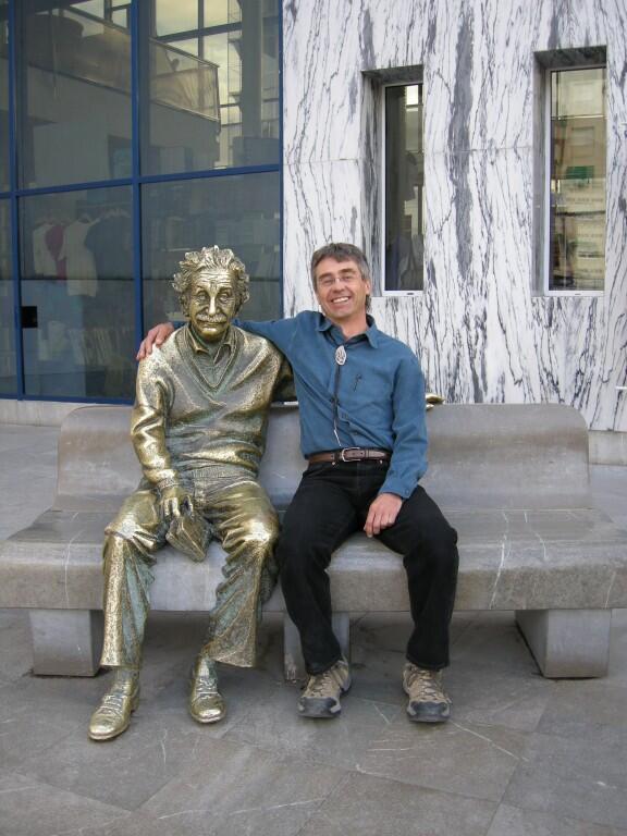 Craig Allen with his arm around a bronze sculpture of Albert Einstein.