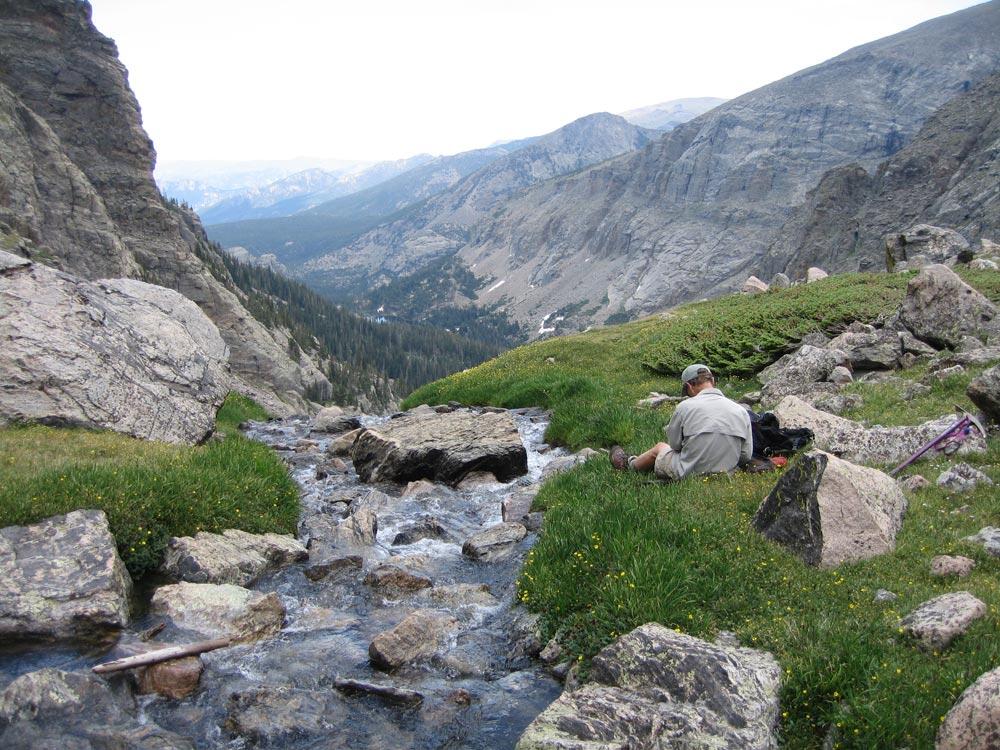 USGS scientist recording data near alpine waterway