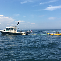 A boat operated by USGS staff tows an instrument that collects geophysical data in in the shallow shoreface near the beach.