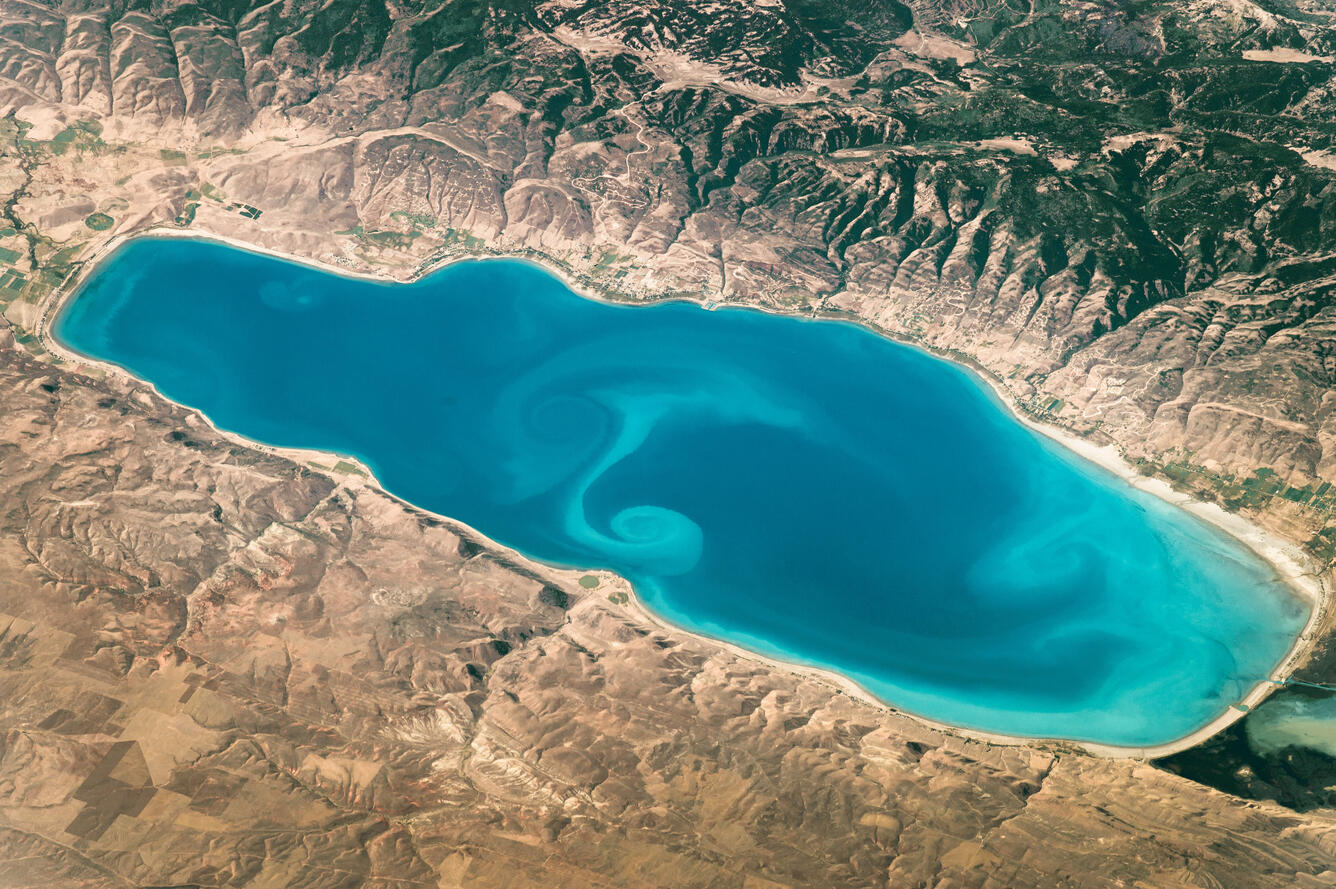 Image of sediment swirls in the bright blue-green Bear Lake taken by astronaut on the International Space Station