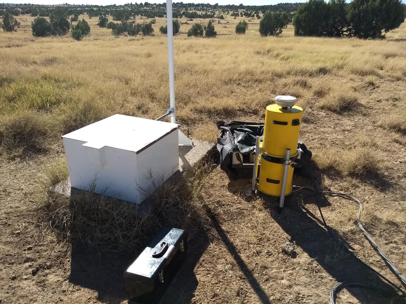 Photograph showing an A-10 absolute gravity meter near a monitoring well.