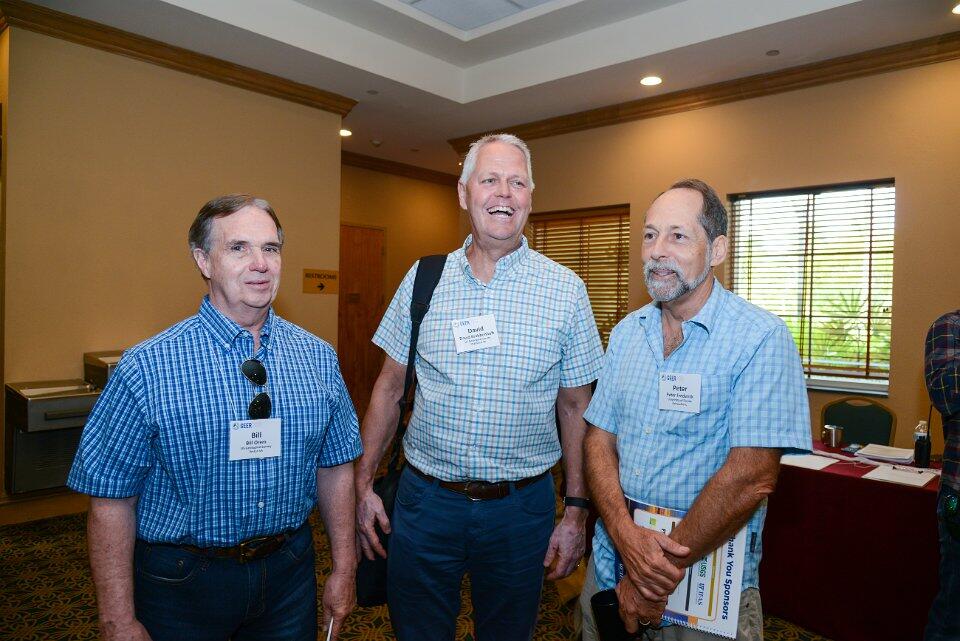 Three male scientists wearing name tags in a conference room
