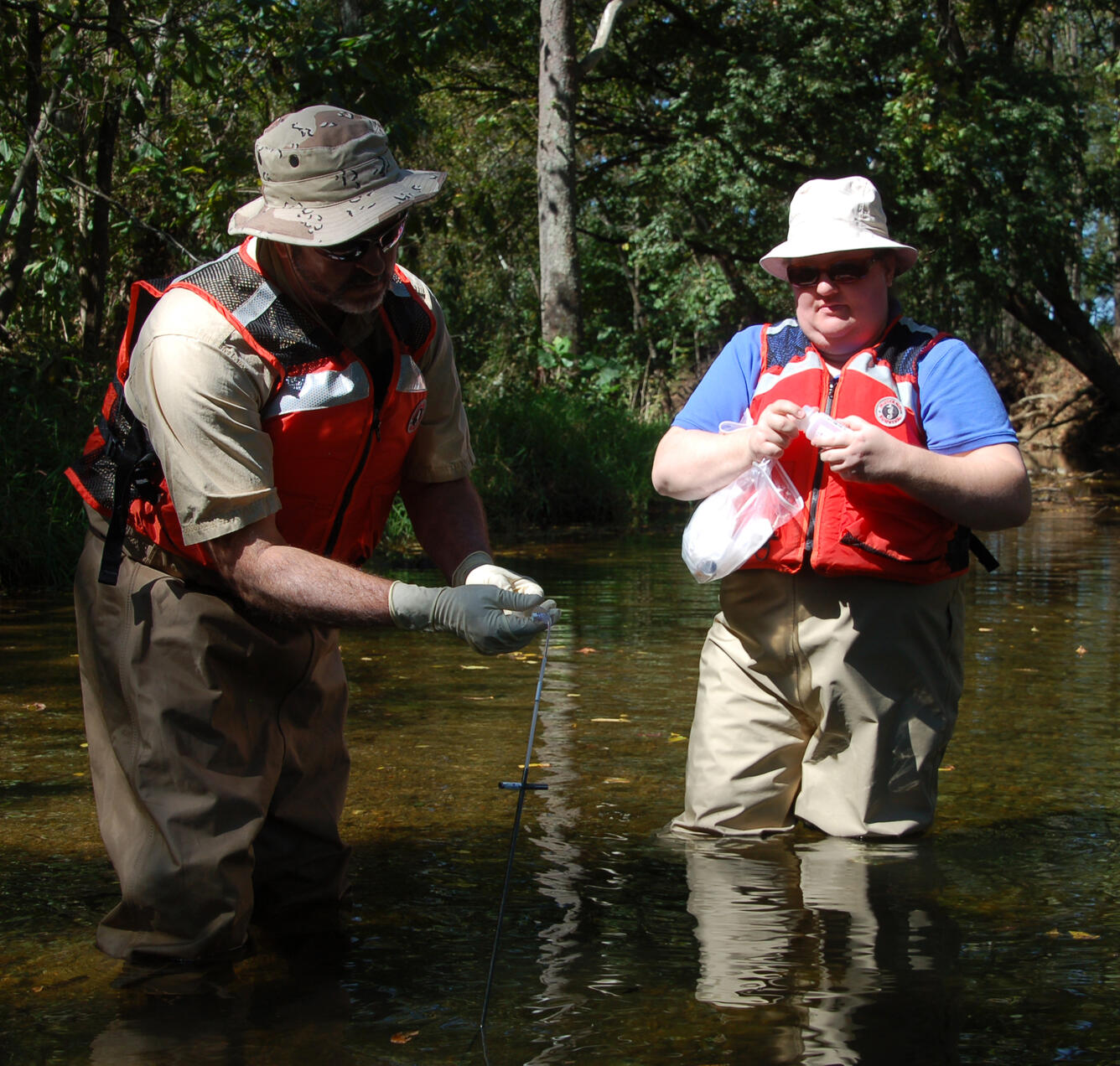 Scientists collect water samples in a stream using a pushpoint sampler