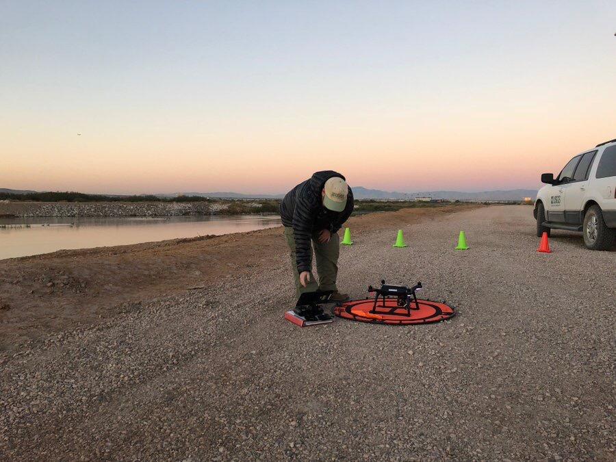 Scientist preparing a drone at dawn next to a river