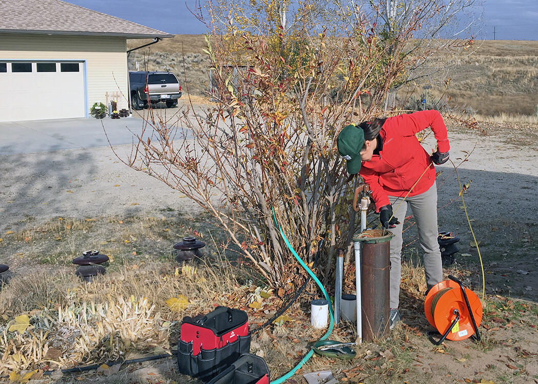 With property owner's permission, a USGS hydrologist collects a water sample from a private well in Gem County, Idaho