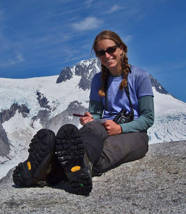 Caroline Van Hemert sitting on a rock with a mountain and glacier in the background