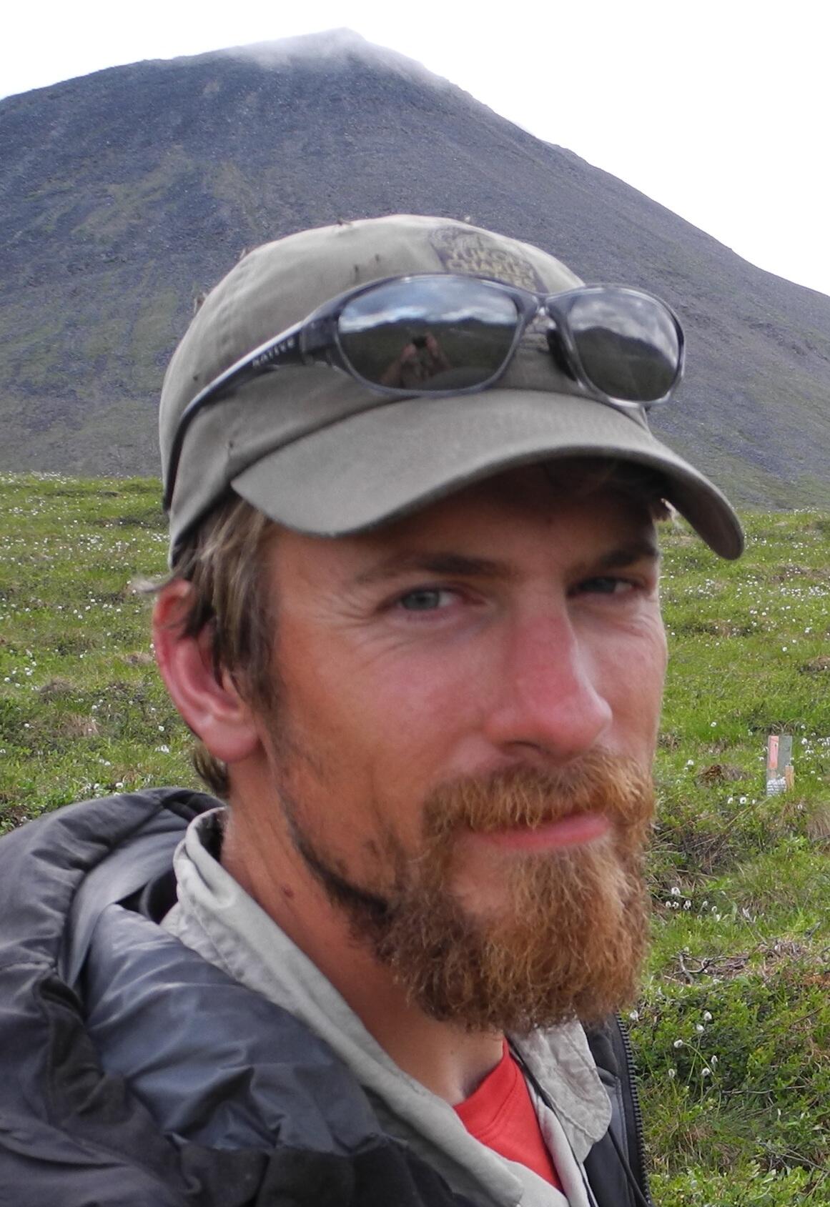 Carson Baughman standing in the tundra of Alaska with a mountain in the background