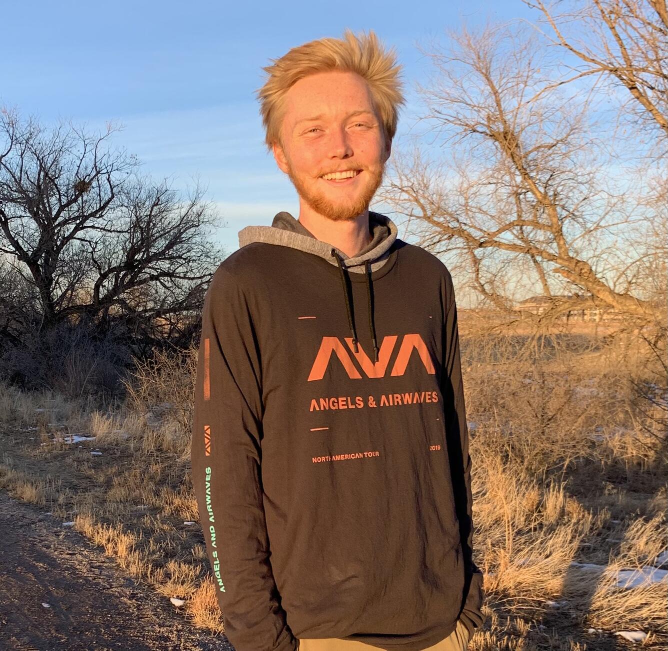 Photo from the waist up of Carter Campbell, standing in front of trees. 
