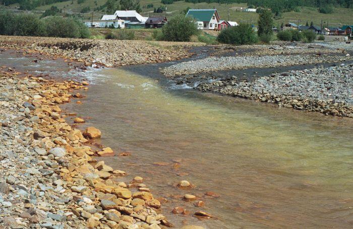 Acid mine drainage from Cement Creek (left) mixes with the waters of the Animas River, Colorado (right) in 1996