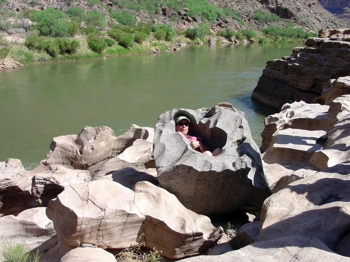 This is a photo of a person sitting in a pothole in the Tapeats Sandstone along the Colorado River.