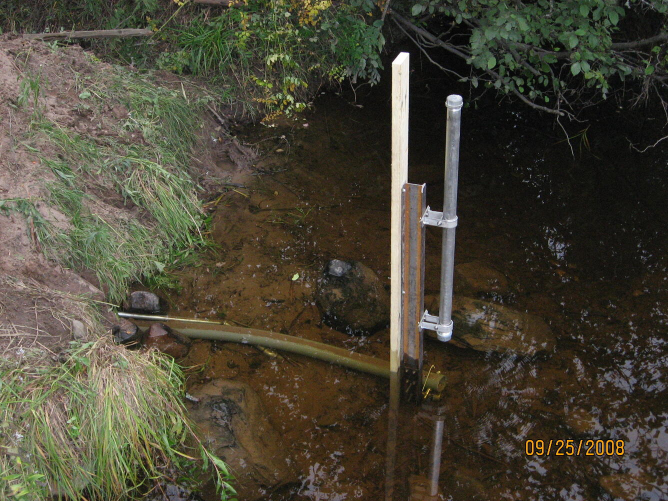 Crest-Stage Streamgage equipment set up at edge of a stream.