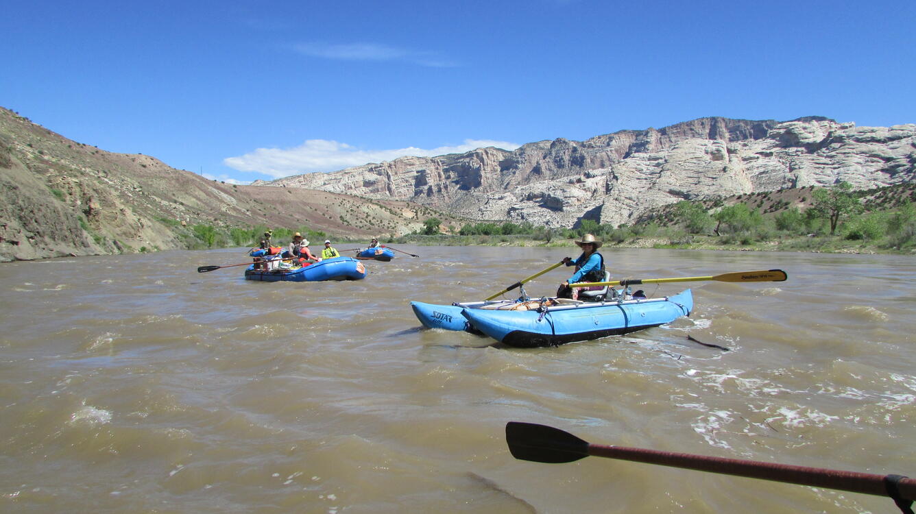 Rafts floating, mountain in distance.