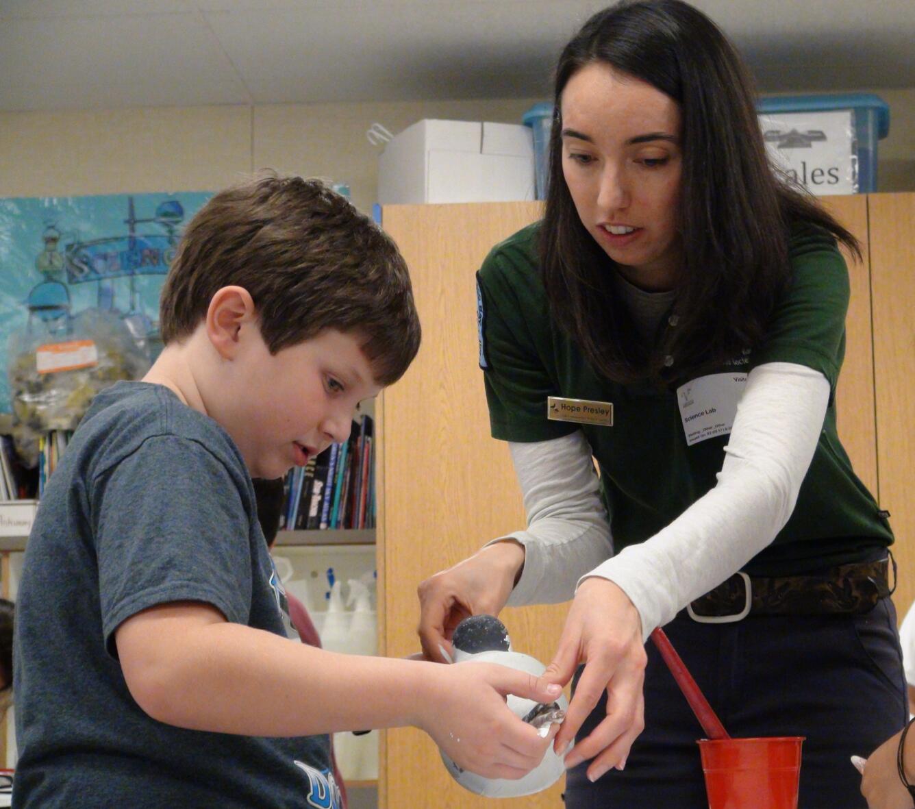 Photo of a USFWS intern helping a student paint a Caspian tern decoy.
