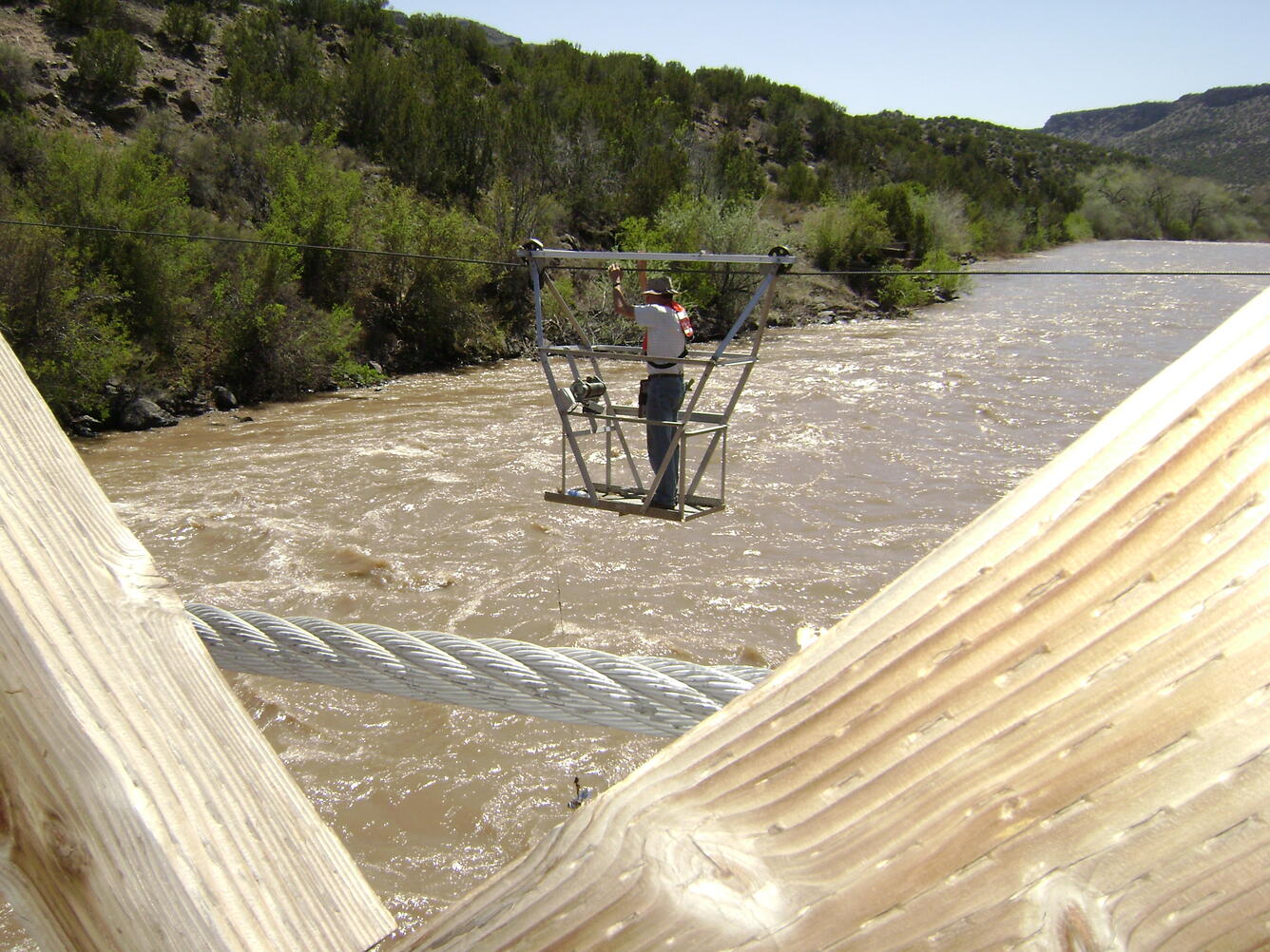 Photo of Supervisory Hydrologist, Thomas Weaver, measuring streamflow from a cableway.