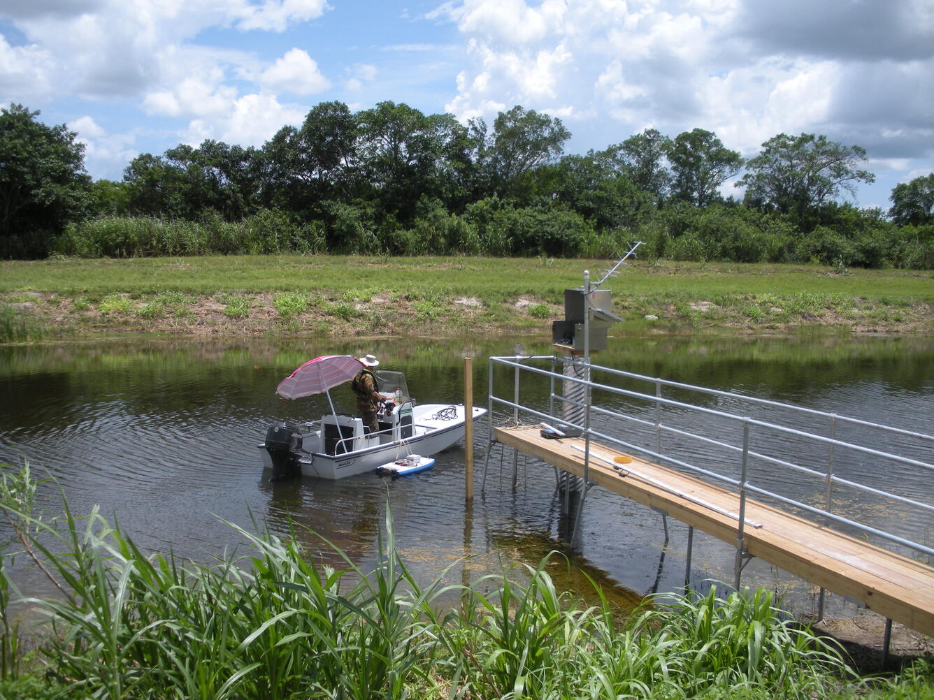 Florida Technician taking measurement on a boat with a ADCP beside channel station. 